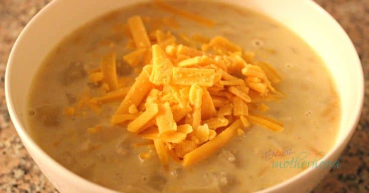 A white bowl filled with crockpot chicken potato chowder and garnished with shredded cheddar