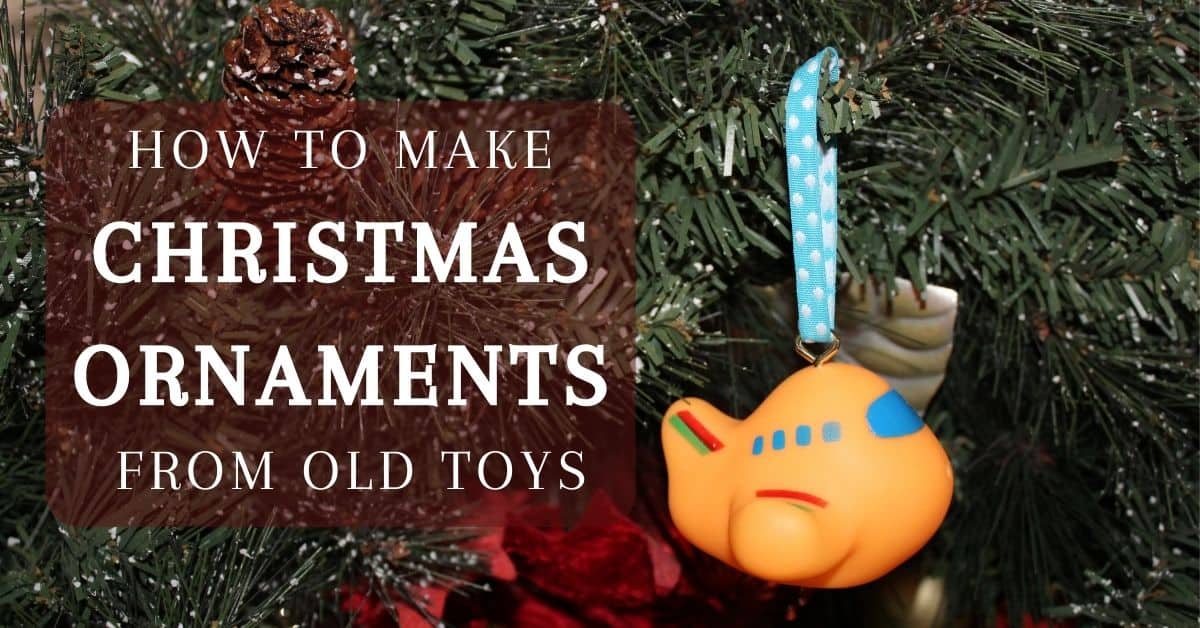 Photo is of a closeup of a Christmas tree focused on an ornament made of a bath toy shaped like a plane, an eye hook, and ribbon. Text overlay reads "how to make christmas ornaments from old toys".