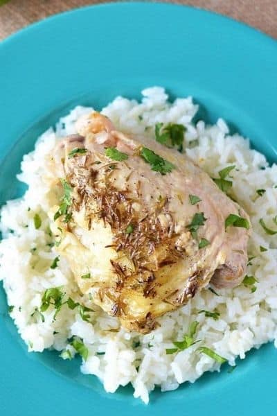 Dump and go slow cooker garlic lime chicken served over rice on a teal plate.