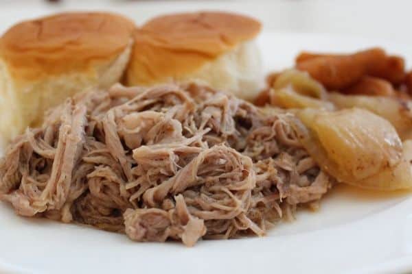 Slow Cooker Pulled Pork with carrots and onions on a white plate and served with rolls