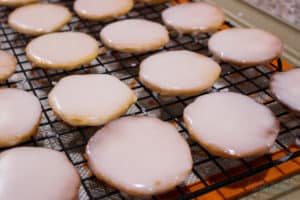 Cookies on black cooling rack after glazing. Cookies are glaze side up waiting for it to set.