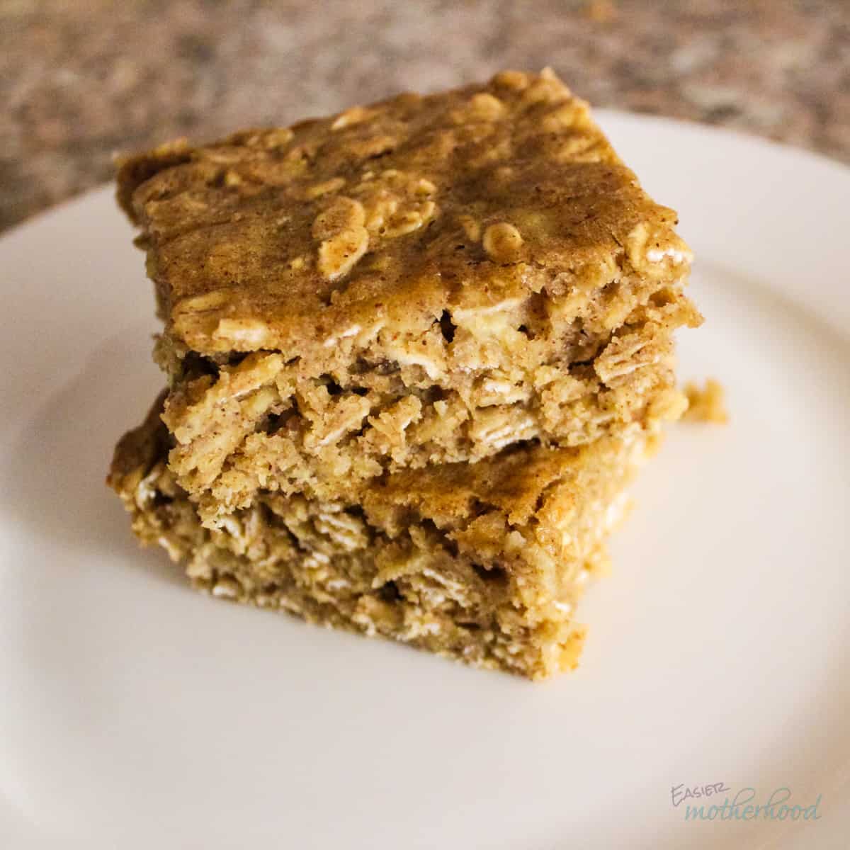 Two soft baked peanut butter oat bars stacked on a white plate
